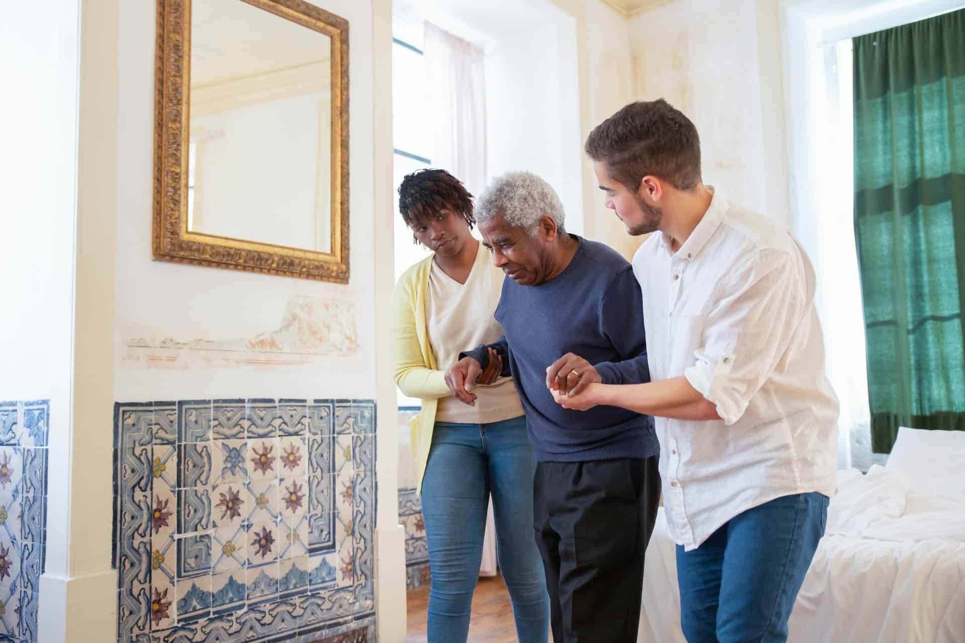 A caring ICARE staff member assisting a resident with a family member nearby